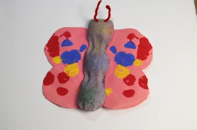 A butterfly made by a child out of milk carton, cardstock, and pipe cleaners.